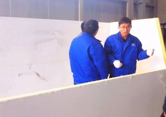 Workers bonding and fixing structural PVC foam core panels during body assembly